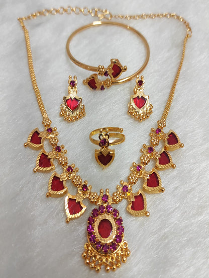 Gold jewelry set with red heart-shaped stones on a white background