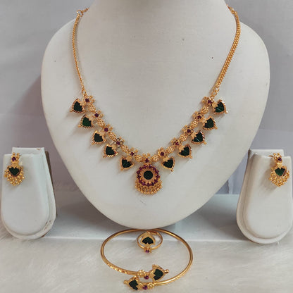 Gold necklace with green and red stones on a mannequin bust, accompanied by matching earrings and bangles.