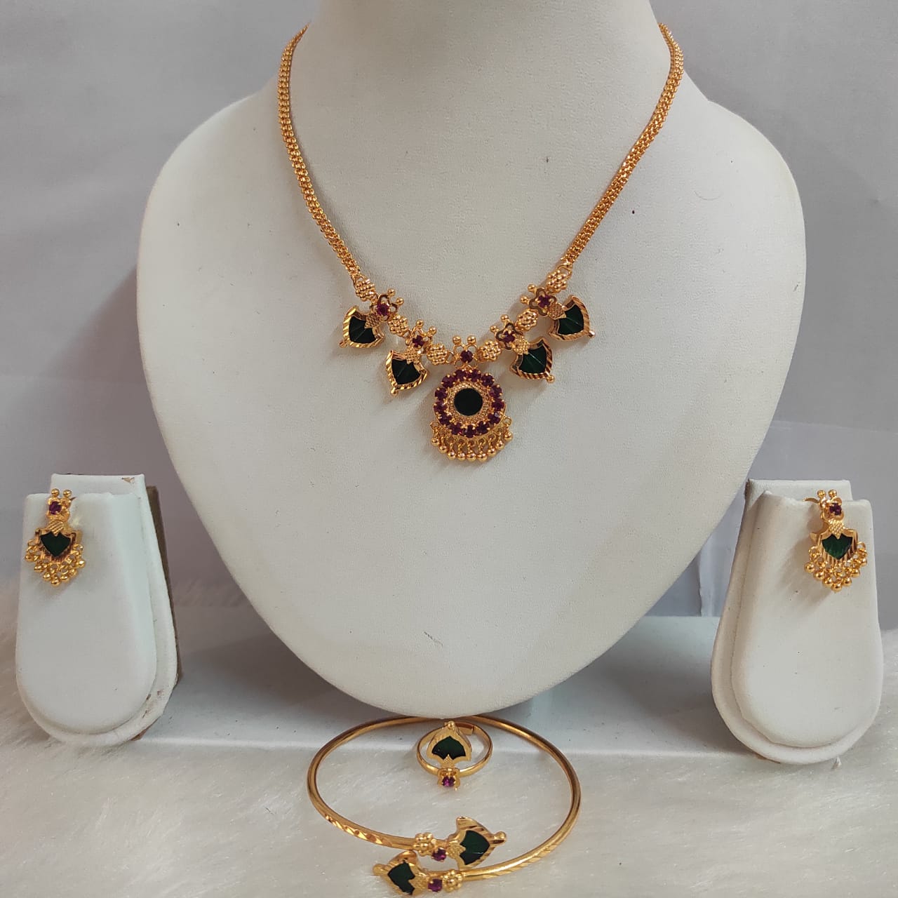 Gold necklace, earrings, and bangles on a mannequin bust with a gray background
