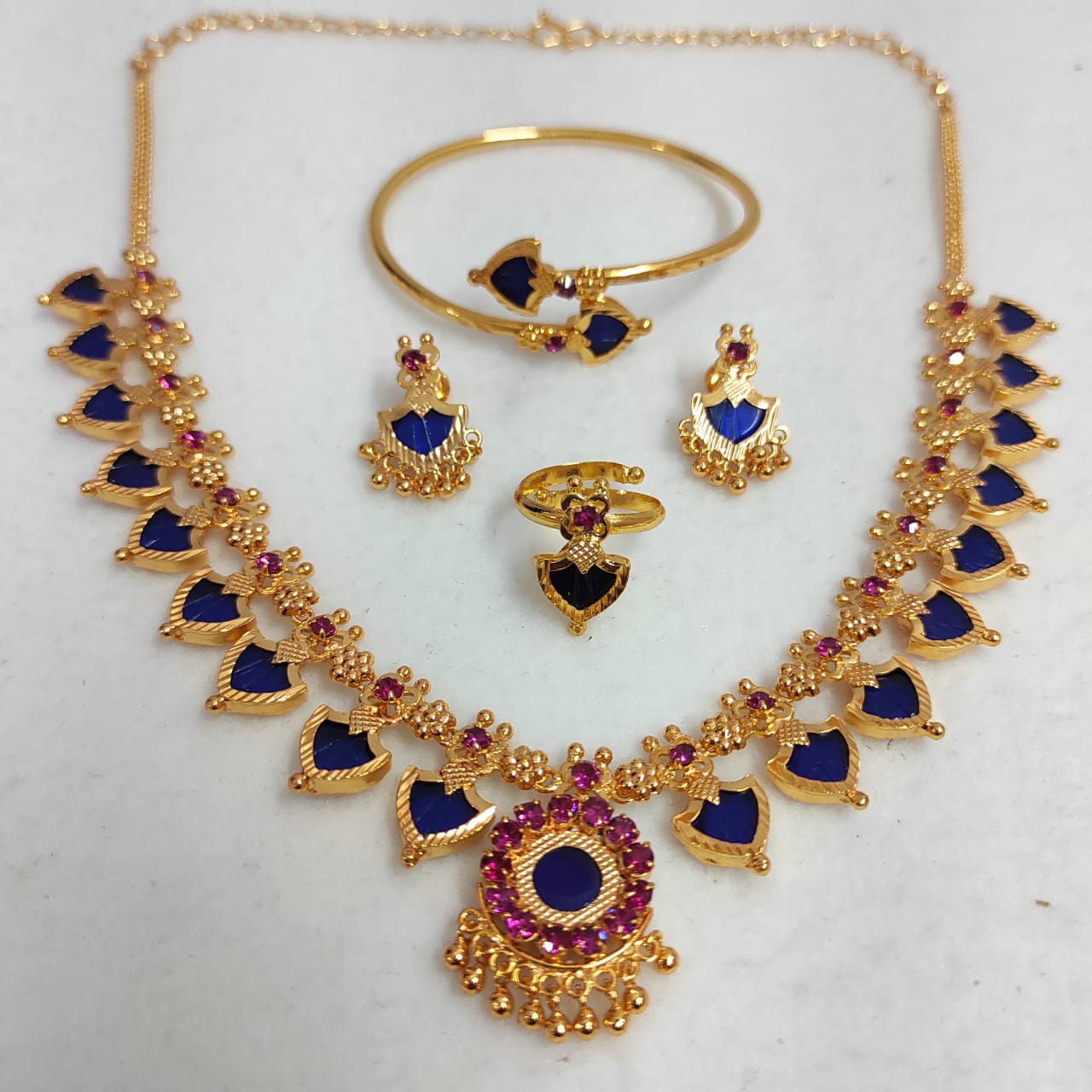 Gold jewelry set with blue and red stones on a white background