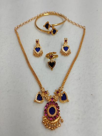 Nandika 2 Charm gold-plated jewelry set featuring a traditional necklace, matching earrings, a ring, and a bangle with deep sapphire blue and ruby stones on a white surface.