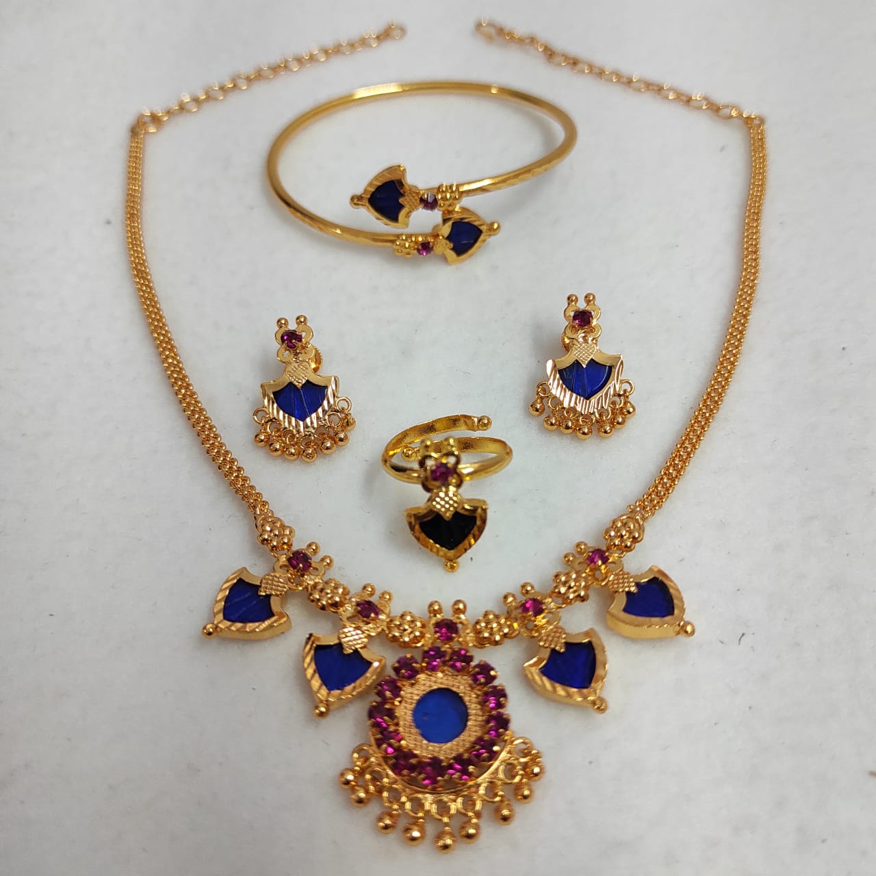Gold jewelry set with blue and red stones on a white background