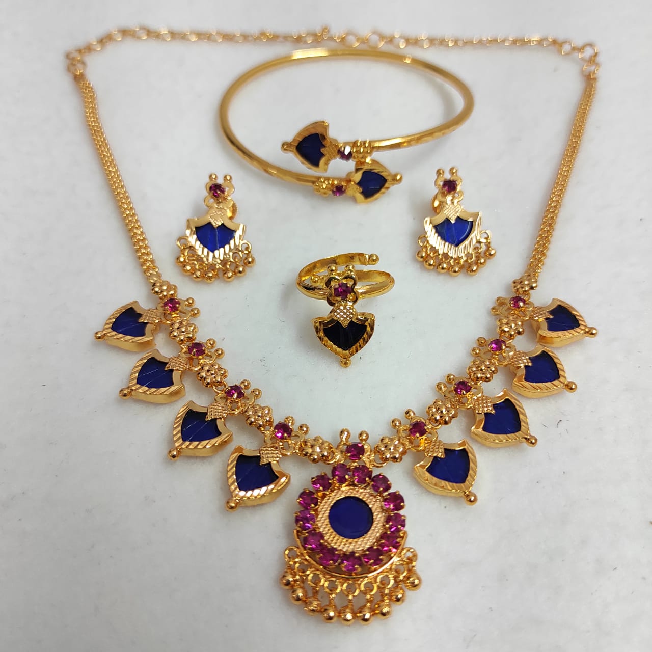 Gold jewelry set with blue and red stones on a white background