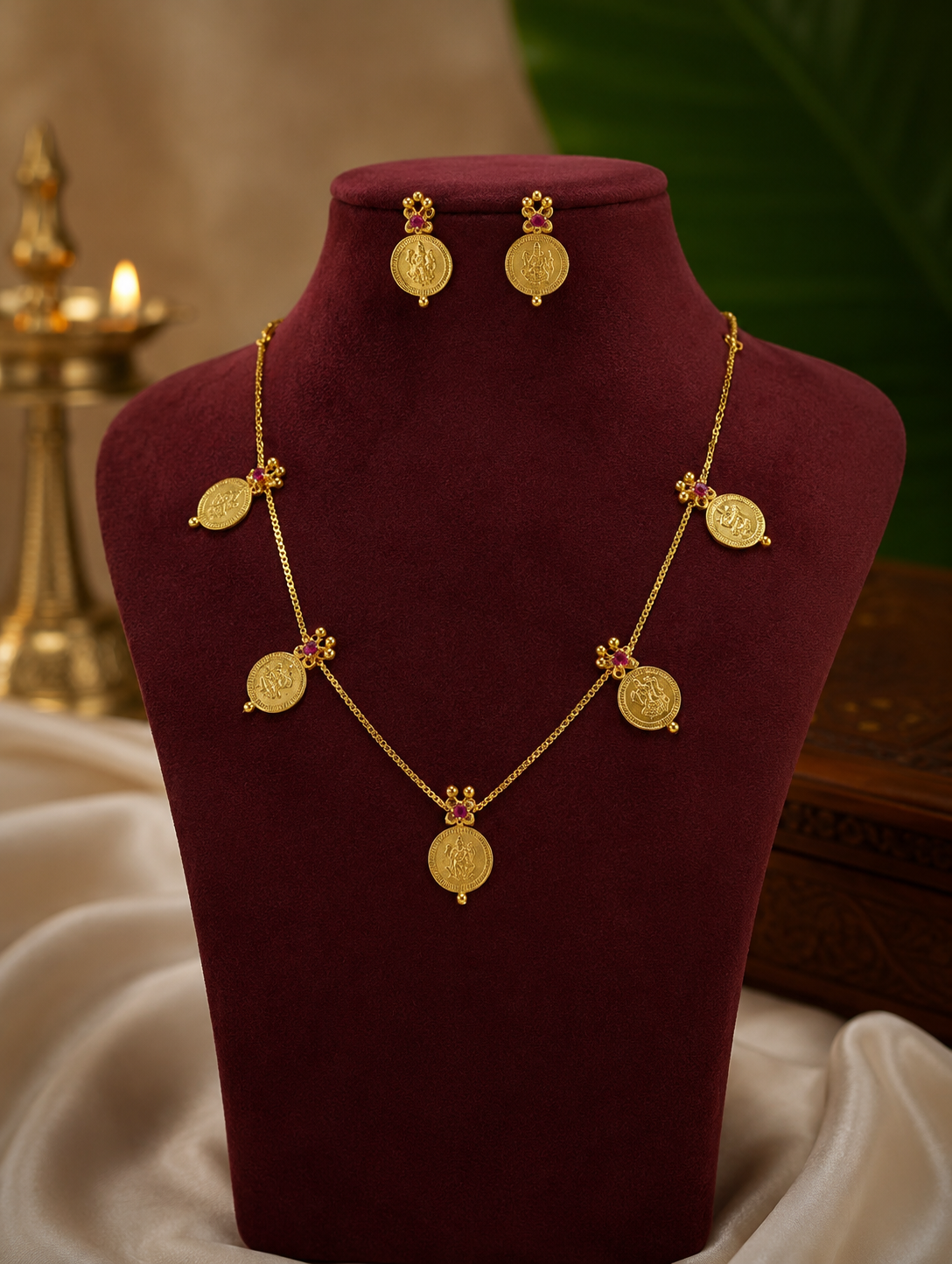 Gold necklace and earrings on a mannequin bust with a soft background