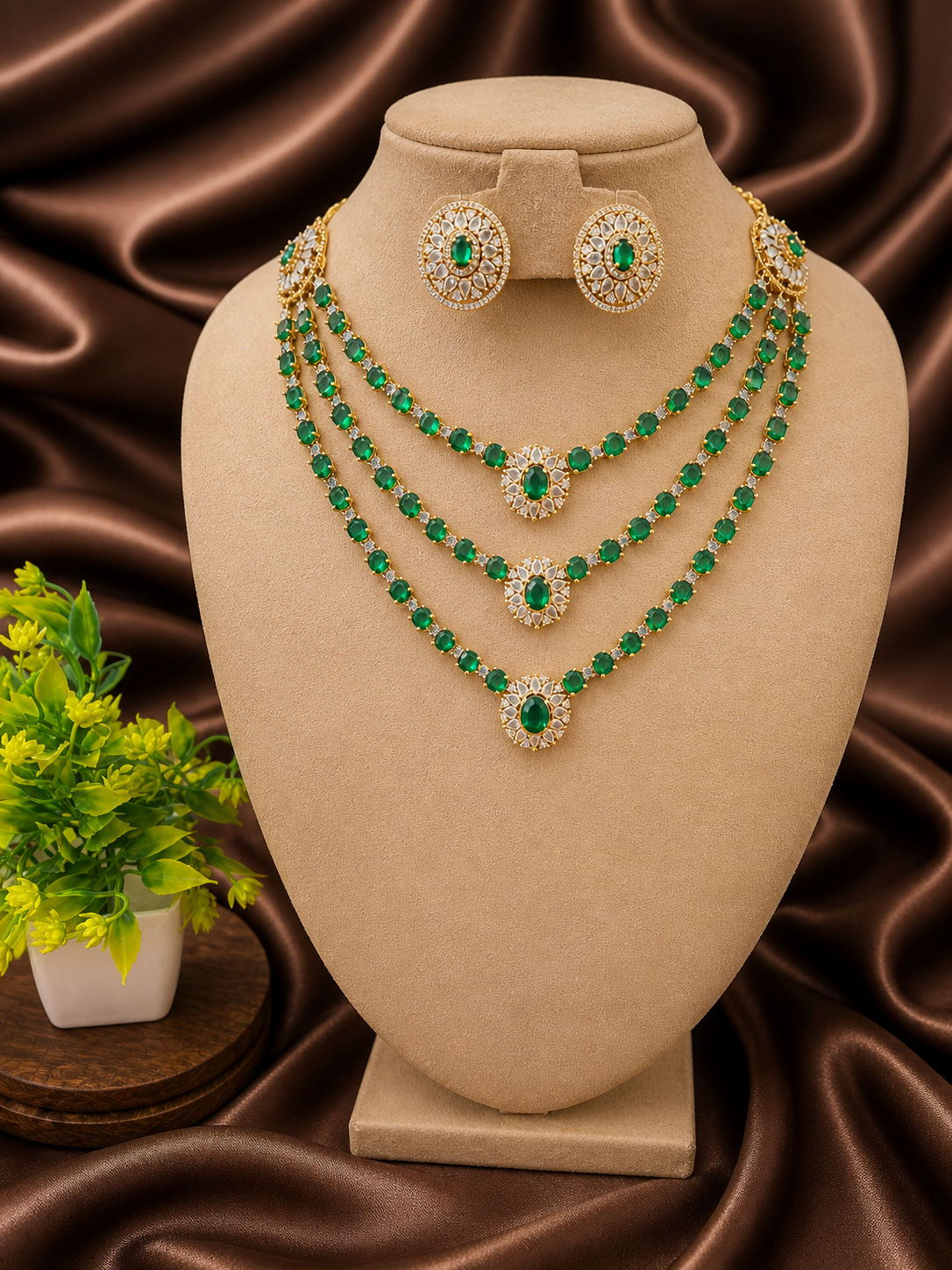Jewelry set with emerald green stones on a beige stand against a brown fabric background