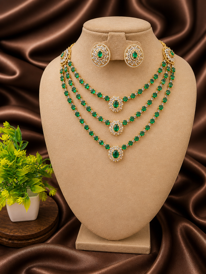 Jewelry set with emerald green stones on a beige stand against a brown fabric background