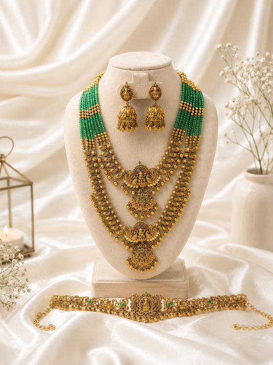 Gold necklace with green beads and matching earrings on a white mannequin bust against a white background.
