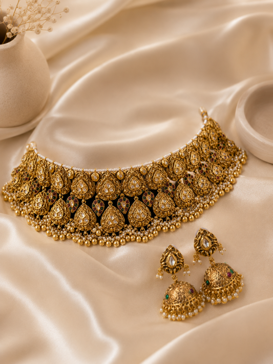 Gold necklace and earrings on a satin surface