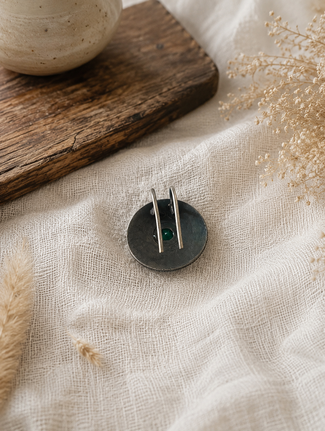 Small round hair pin  with two vertical elements on a textured fabric background