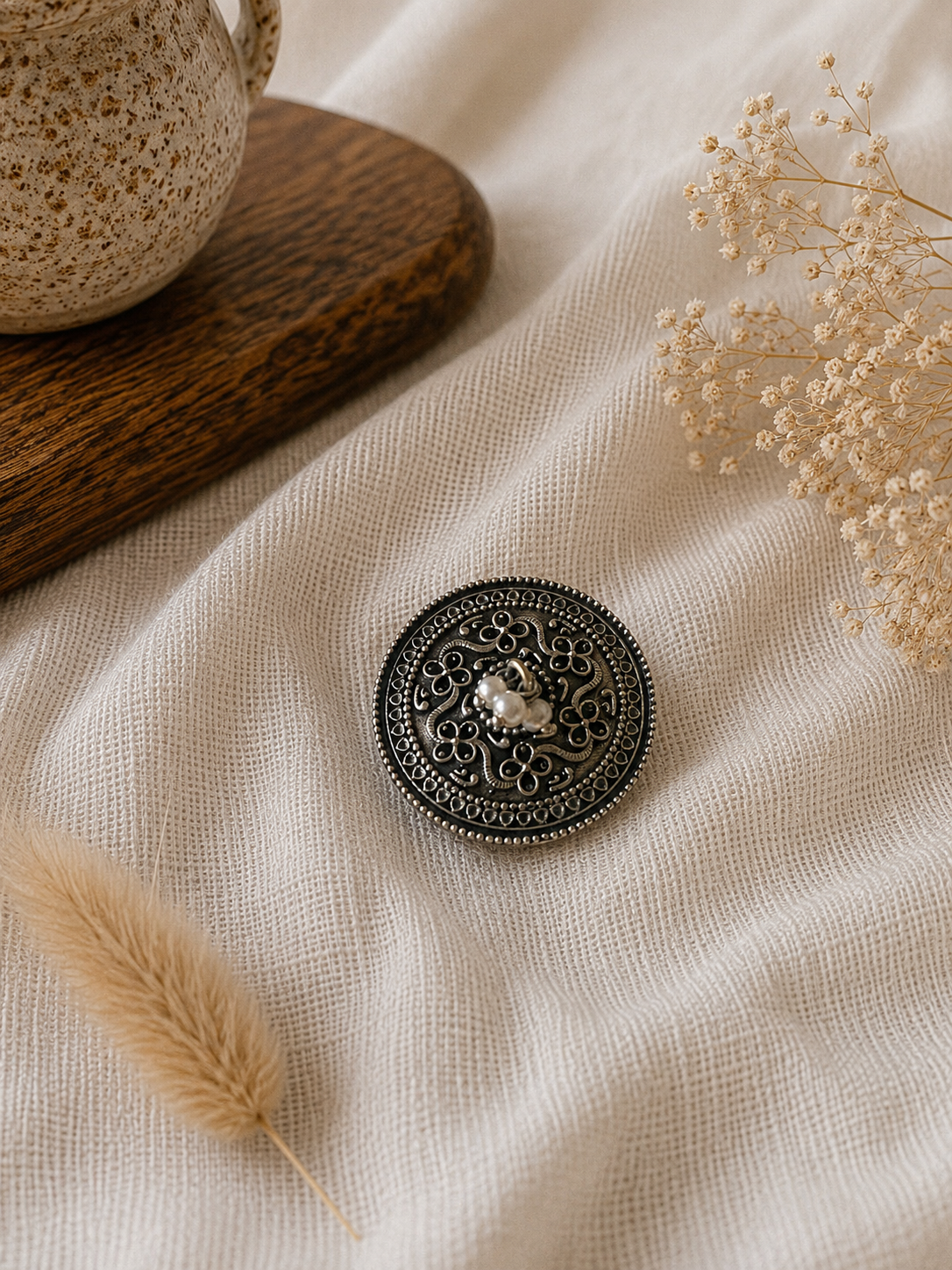 Decorative hair pin on a textured fabric surface with dried plants