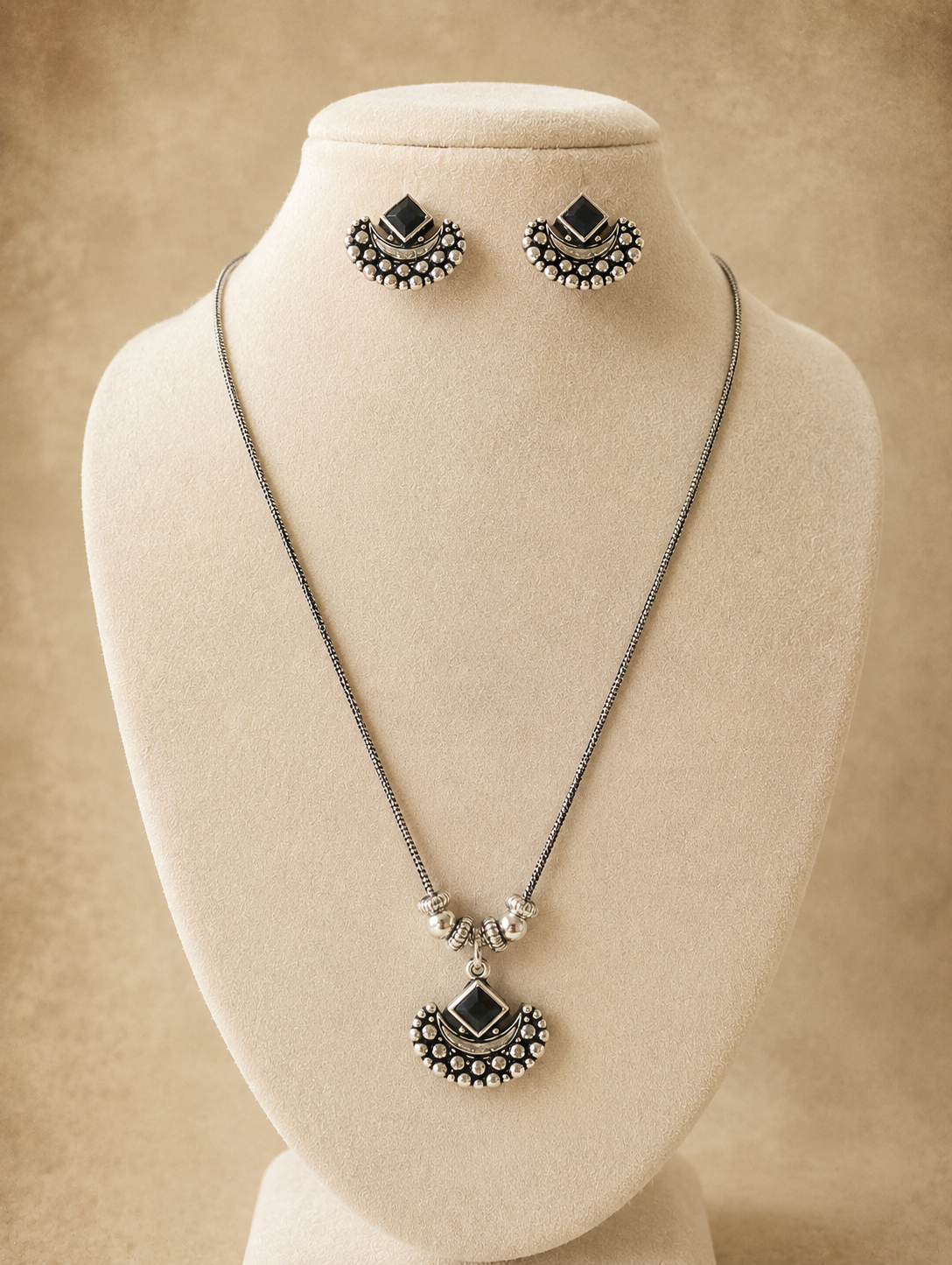 Jewelry set with necklace and earrings on a mannequin bust against a beige background