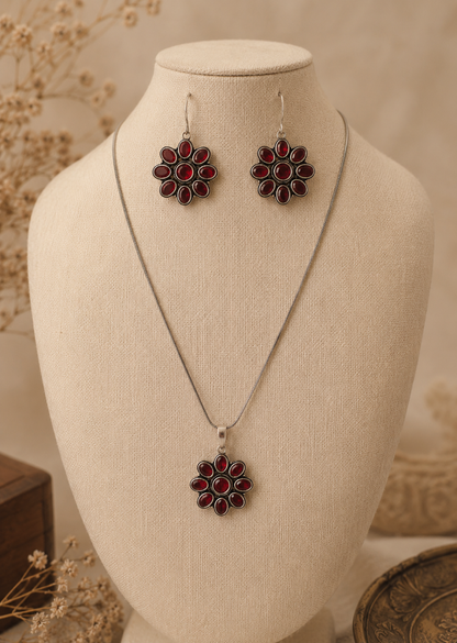 Silver necklace and earrings with red floral designs on a mannequin bust.