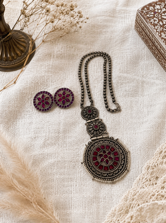 Ornate necklace and earrings on a textured surface with decorative elements.