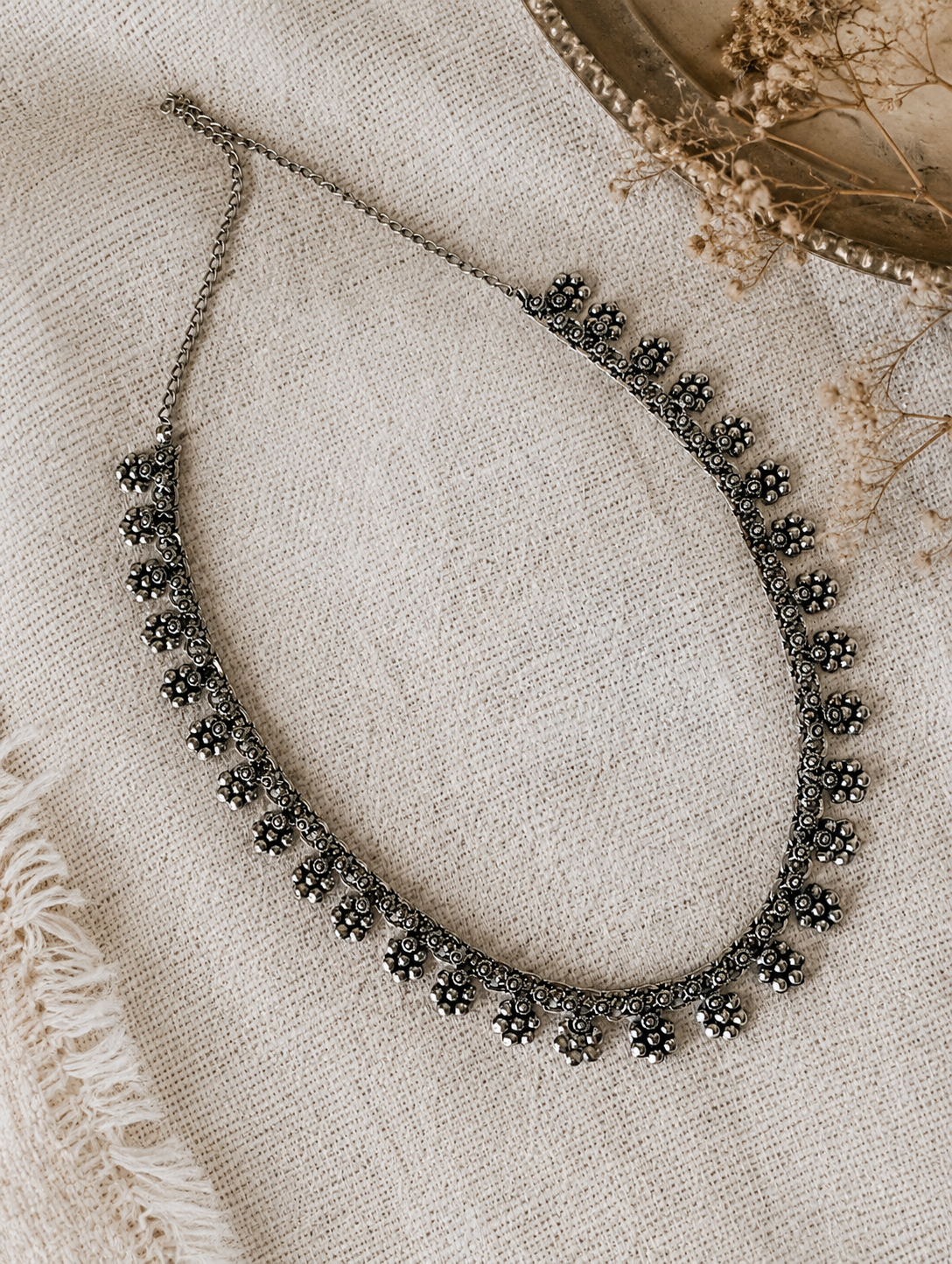 Necklace with floral design on a textured beige surface