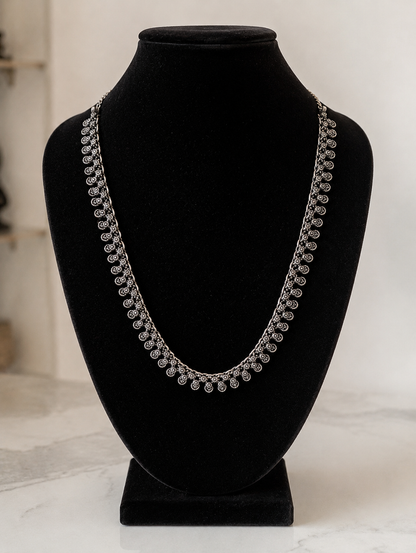 Silver necklace on a black mannequin bust against a white background