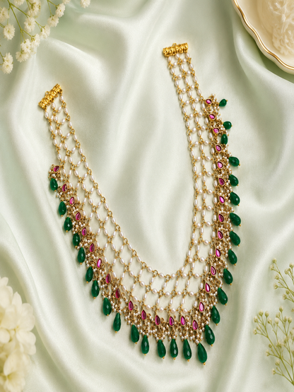 Delicate necklace with green and red stones on a light fabric background