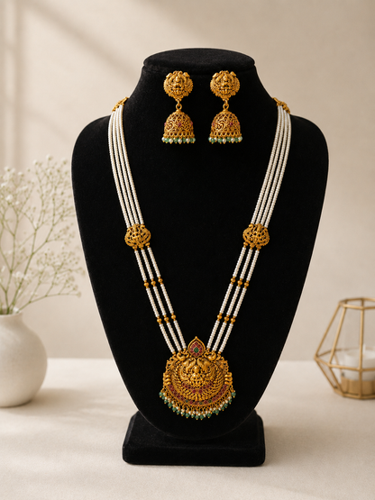 Gold necklace and earrings on a black stand with a neutral background