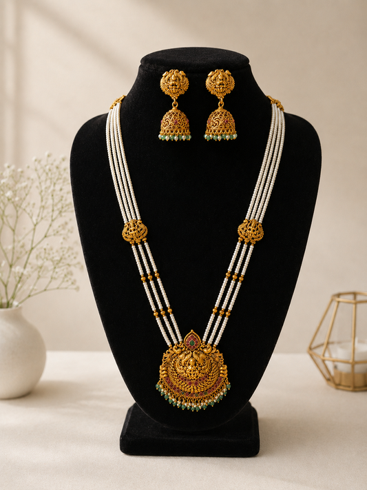 Gold necklace and earrings on a black stand with a neutral background
