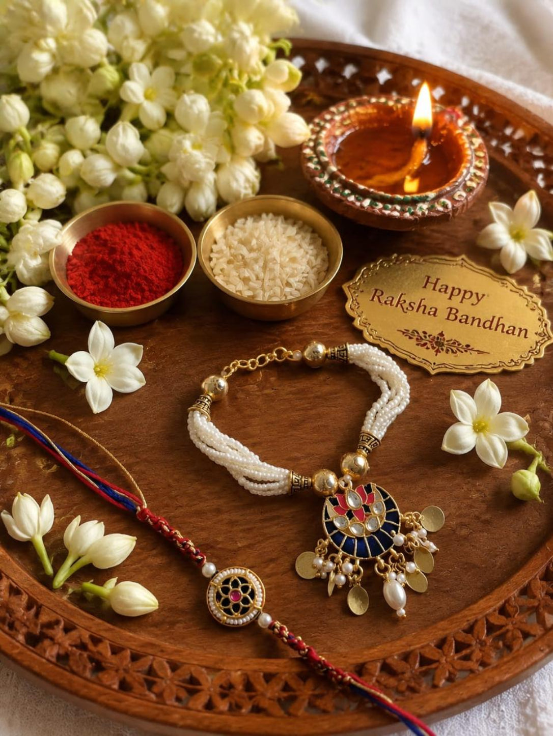 Handcrafted Bhaiya Bhabhi Rakhi set featuring a multi-strand white pearl Lumba bracelet with a blue Meenakari pendant and a matching round thread Rakhi.