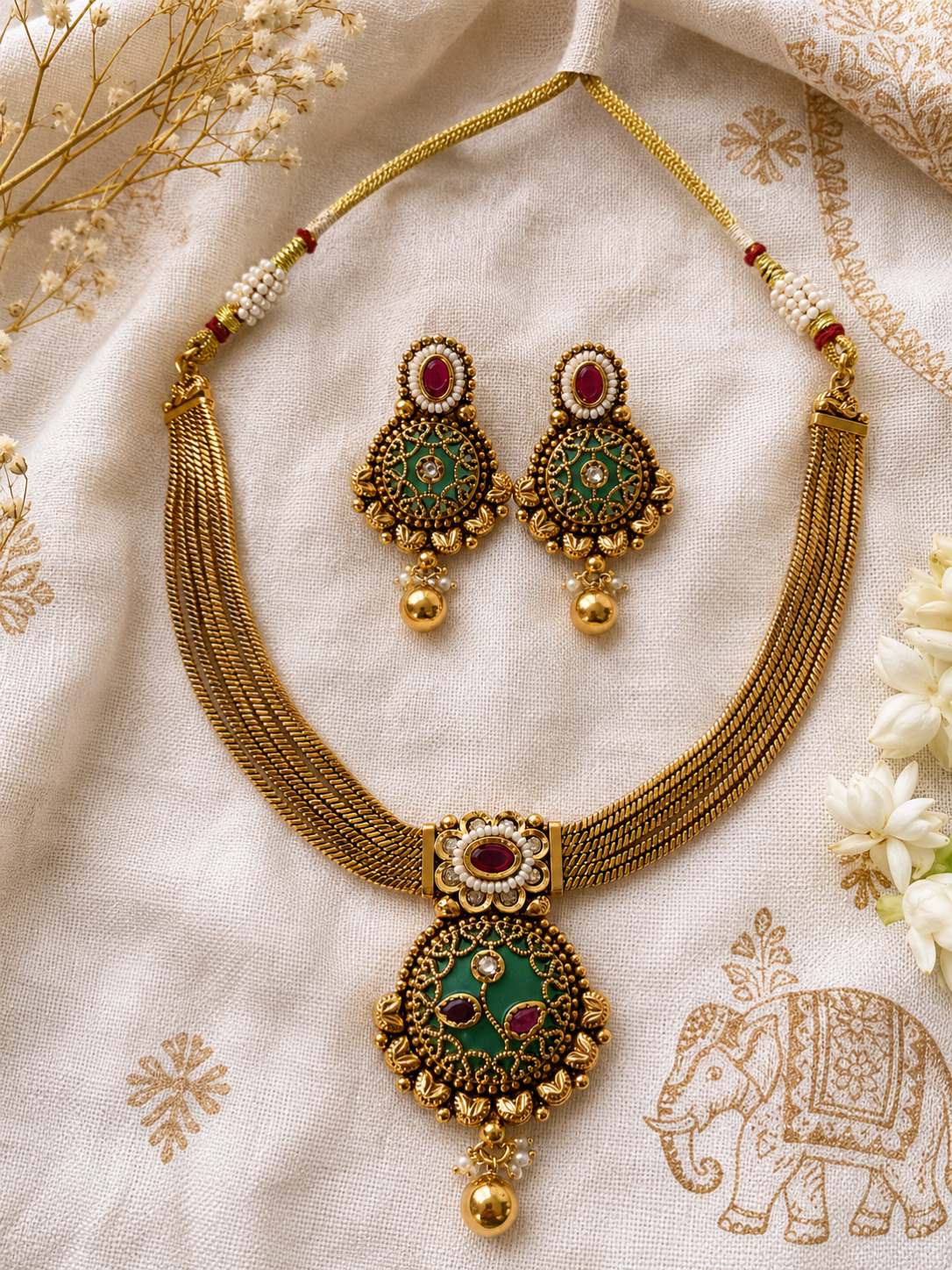 Traditional Indian gold choker necklace set featuring green Meenakari artwork, ruby gemstones, and pearls for bridal and festive occasions.