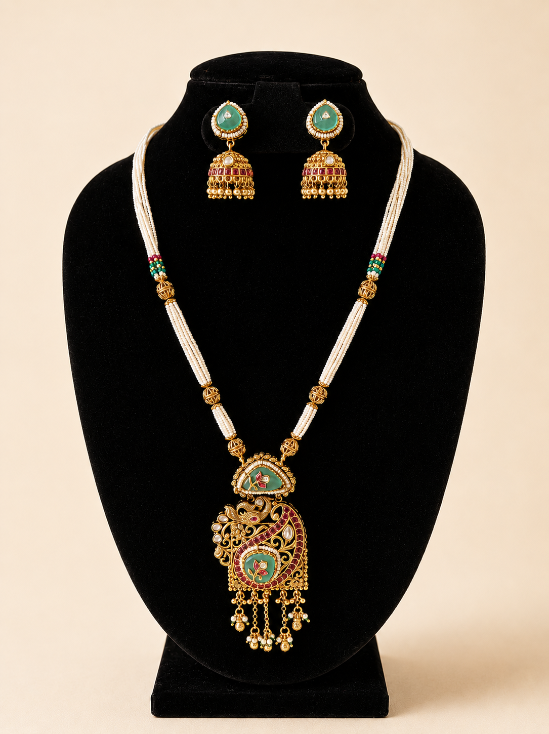 Jewelry set with necklace and earrings on a black stand against a beige background