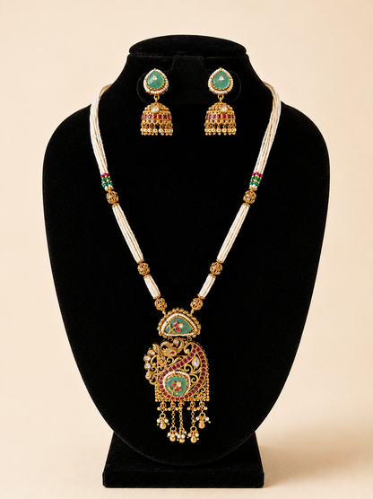 Jewelry set with necklace and earrings on a black stand against a beige background