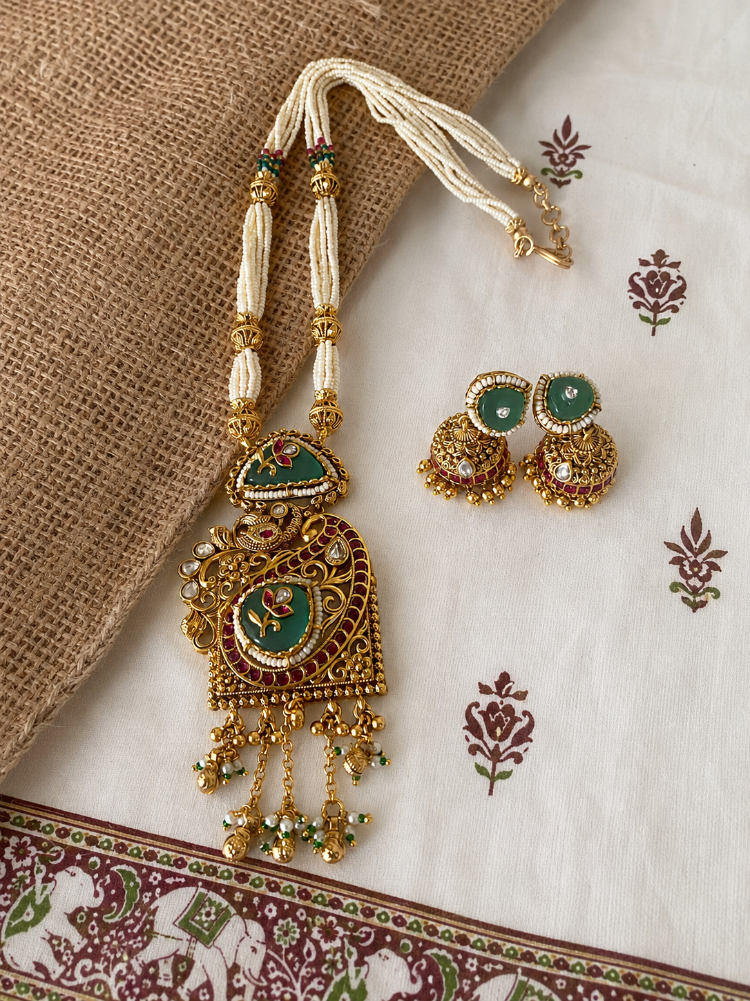 Antique gold pearl haram necklace set with a large green enamel pendant and matching Indian Jhumkas, ideal for bridal and ethnic festive wear.