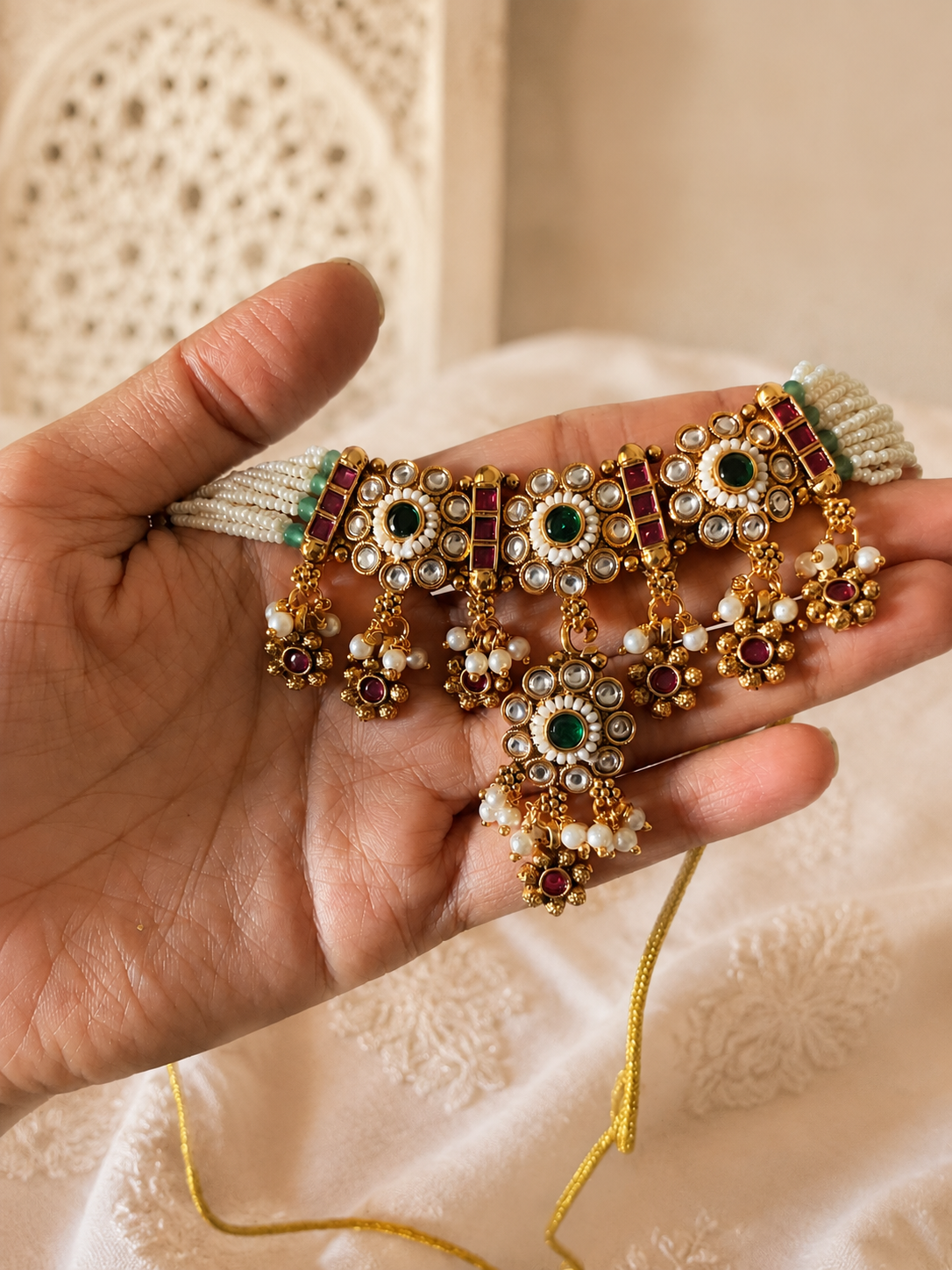 Royal Indian bridal choker necklace featuring multi-layered seed pearls, antique gold Kundan work, and ruby-emerald gemstone settings for traditional festive and wedding wear.