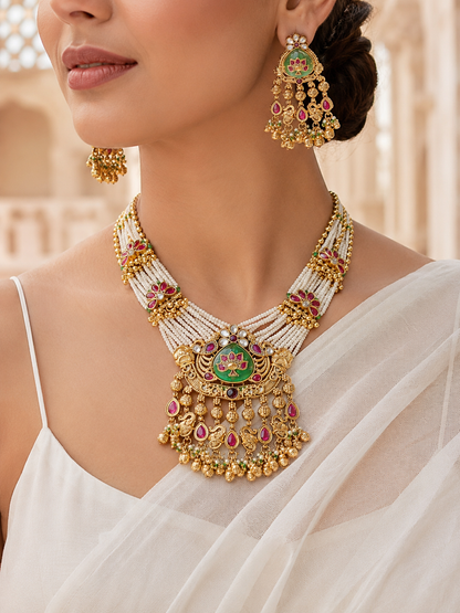 A close-up shot of a model wearing the antique gold-plated multi-strand pearl necklace with a large lotus motif pendant and matching statement earrings, styled with a white saree against a soft blurred background.