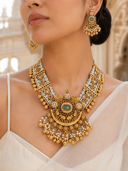 Close-up of a woman wearing an ornate gold necklace and earrings with a blurred architectural background.