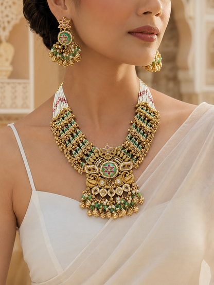 Woman wearing a gold necklace and earrings with a blurred architectural background