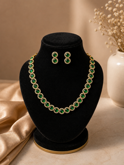 Premium gold-plated choke necklace set intricately embedded with alternating rich green emeralds and deep red ruby stones in a seamless, flexible collar design. The matching multi-stone drop earrings are placed at the center, all beautifully arranged on soft cream satin fabric.