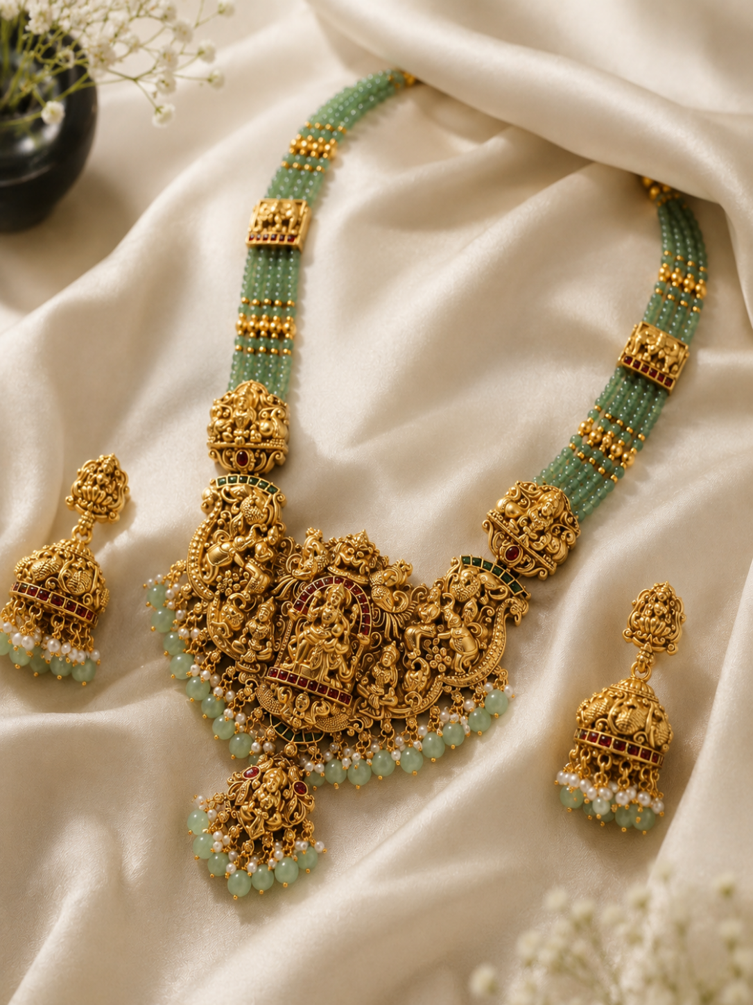 Gold and green jewelry set on a white fabric background