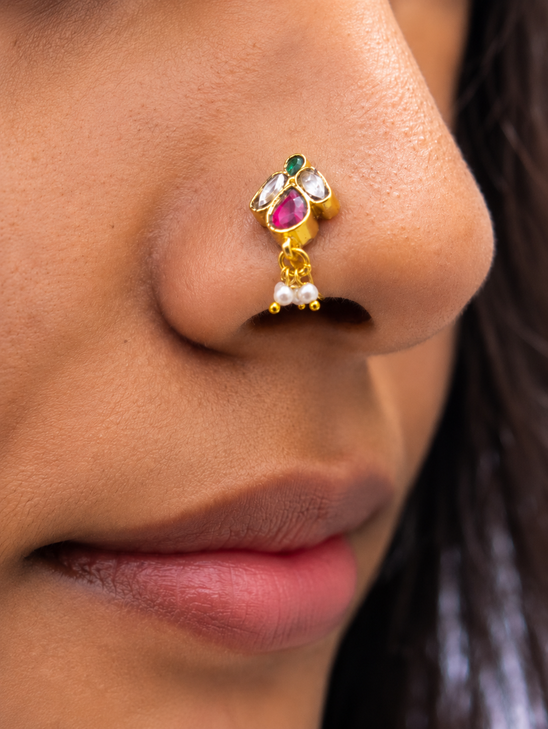 A model wearing the SP015 non-piercing traditional Indian nose pin clip, highlighting how the gold-plated Jadau Kundan jewelry fits comfortably on the nostril.