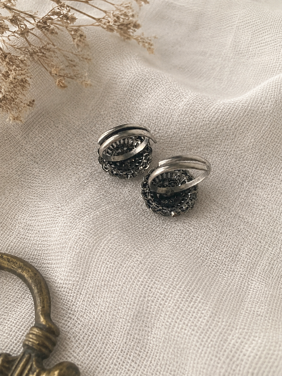 Pair of silver earrings with black stones on a textured beige fabric background