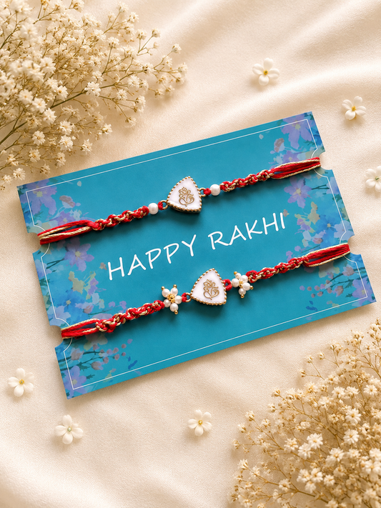 Two handcrafted designer Rakhis featuring triangular white charms with gold Ganesha icons, pearl accents, and braided red threads displayed on a blue card.