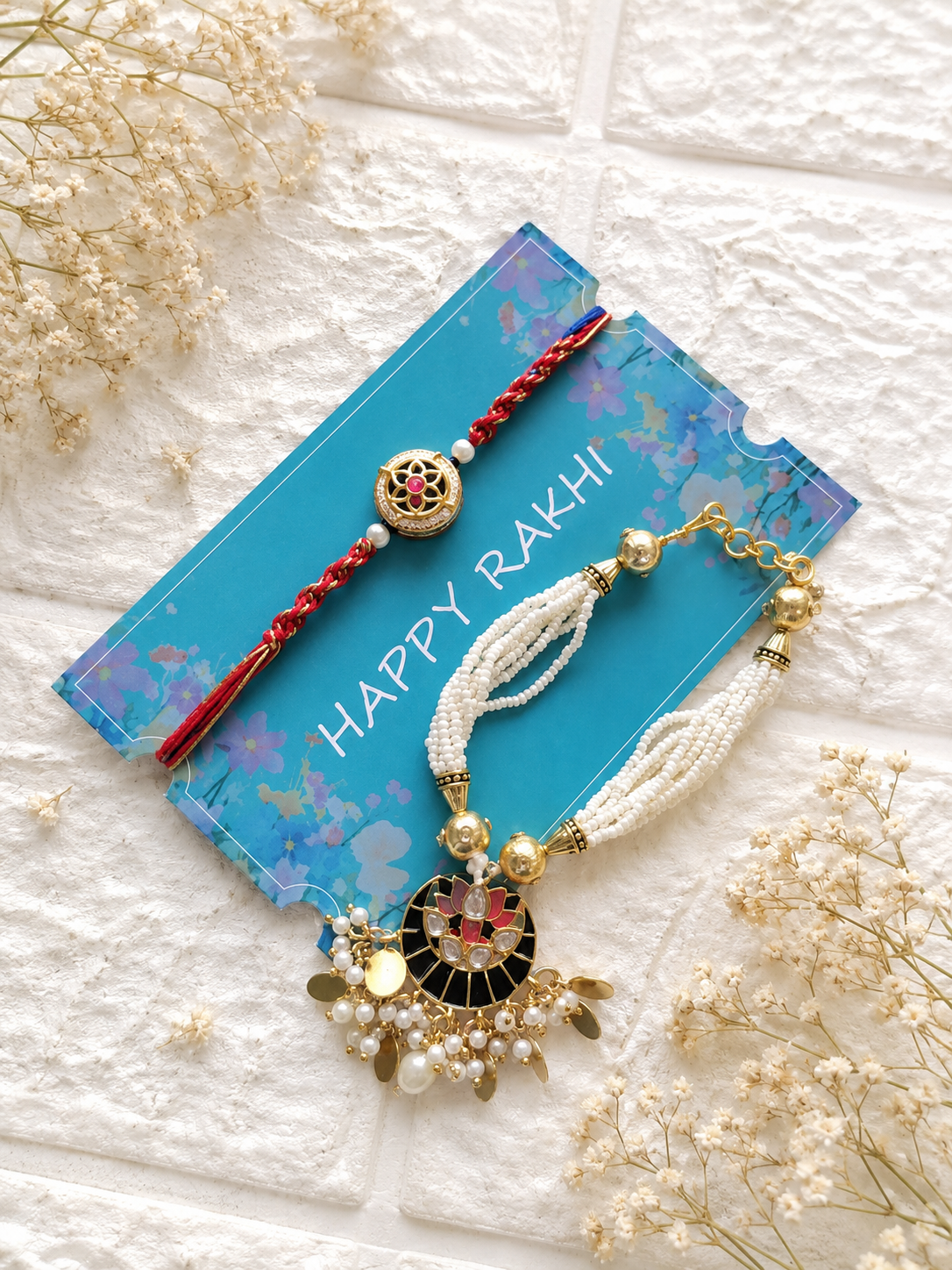 Handcrafted Bhaiya Bhabhi Rakhi set featuring a multi-strand white pearl Lumba bracelet with a black and pink lotus pendant next to a matching round thread Rakhi.