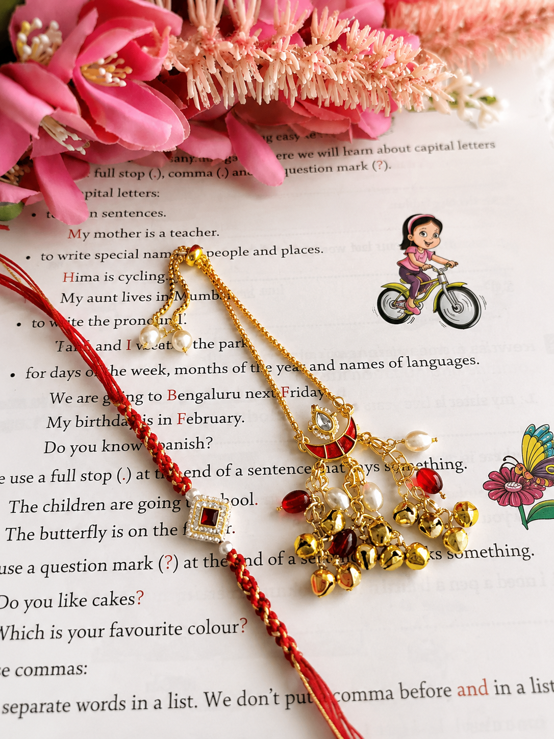 Handcrafted Bhaiya Bhabhi Rakhi set featuring a gold-toned Lumba hanging ornament with a red crescent charm, small bells, and a matching red braided thread Rakhi.